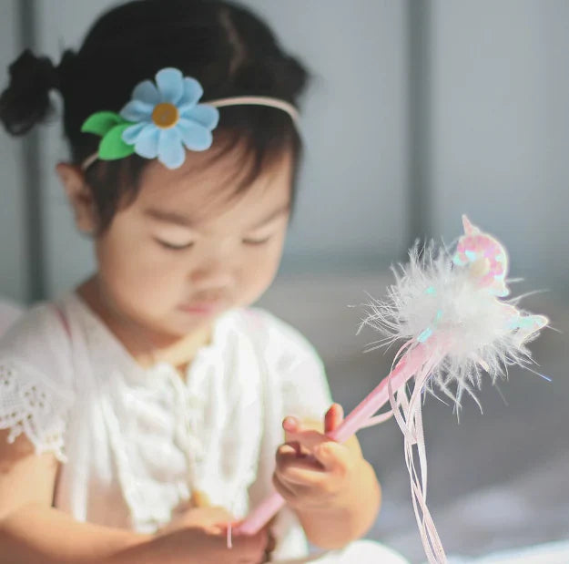 Young girl holding a unicorn feather wand.