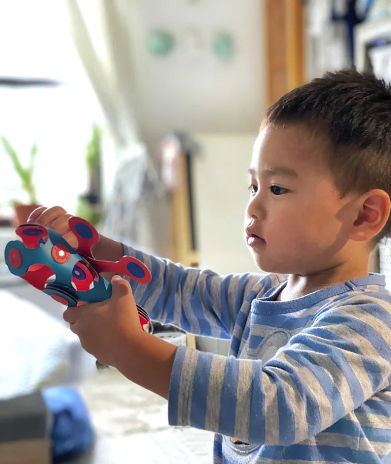 Boy holding a blue and red bendable model.