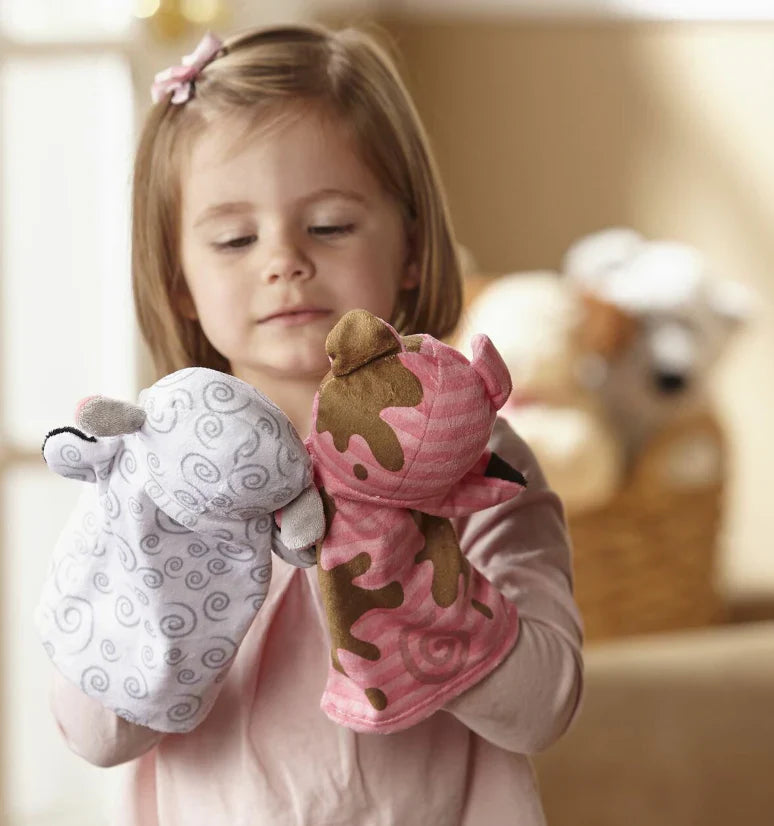 Young girl holding two hand puppets.