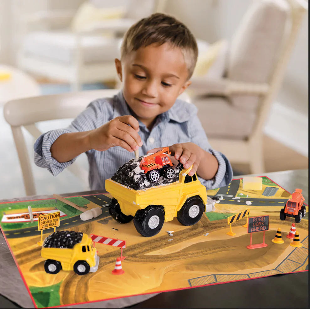 Boy playing with construction vehicles on a playmat.